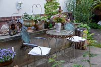 Old garden furniture in courtyard with collection of pots