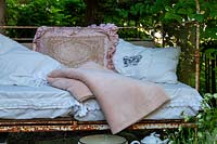 Old bed frame as a bench with pillows and a blanket