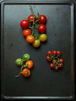 A display of  'Tommy Toe' small, and 'Sweet Bite', large, tomato trusses on a metal baking tray.