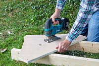 Man using jigsaw in order to create the handle for carrying the coldframe