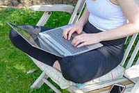 Young girl using a laptop while working and studying from home in the garden.  