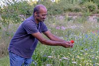 Guru Sharma unfurling a poppy flower in the wild flower meadow garden he helped to create. 