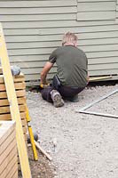 Man measuring space for patio with tape measure. 
