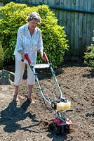 Woman using Mantis tiller on area of border to be replanted