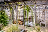 Courtyard garden with timber pergola, rill, galvanised trough water feature and planting including Stipa tenuissima, S. gigantea, Phlomis russeliana, Perovskia 'Blue Spire', irises and silvery stachys at Am Brook Meadow, Devon in August. 