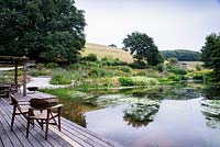 Timber decking brings the house into close contact with the large pond that occupies the site of a former intensive pig unit at Am Brook Meadow, Devon in August. 