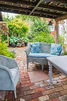 Wicker furniture on verandah overhang, brick paving and view to garden