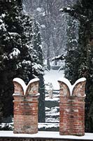 Decorative brick chimney pots with view to sculpture in snow covered garden