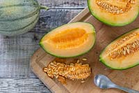 Melon 'Irina' quartered to reveal the fresh and seeds inside - seeds removed with a spoon