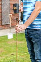 Man hammering a fencing pin into ground with rubber mallet