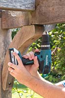 Man using an electril drill to predrill a fine hole in timber 