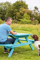 Man and his dog sitting at newly assembled picnic bench in meadow