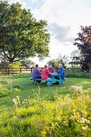 People sitting at newly assembled picnic bench in meadow