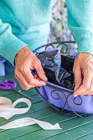 Woman fitting two liners inside metal hanging basket ready for planting 
