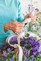 Woman trying a knot with three ribbons to hang basket