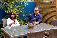 Small garden in West London with owners Noreen and Fawad Ahmad sitting at a table in the patio area. 