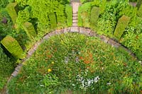 View of the Wild Garden with steps in gravel. Columns of Taxus baccata. Image taken from drone. The garden has been created since 1987 by garden writer Anne Wareham and her husband, photographer Charles Hawes.