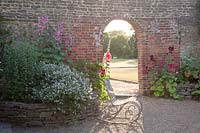 Archway through old brick wall. Loseley Park, Surrey, UK. 