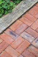 Red brick path edged with oak sleeper. 