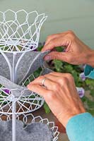 Woman adding the grey felt lining to the tiered metal planter. 