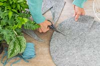 Woman cutting splits in grey felt using scissors to enable the lining to fit neatly in basket. 