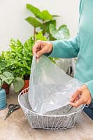 Woman lining basket with plastic. 