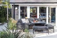 Patio with modern lounge furniture, mixed textured planting and view to statement pot and arch . 