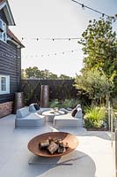 Paved area with modern lounge furniture and firepit. 