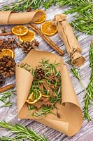 Scented fire starters made with Salvia rosmarinus syn. Rosmarinus - Rosemary - in brown paper with cinnamons sticks, orange slices, star anise and pine cones