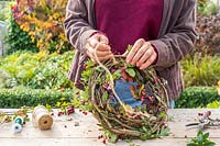 Woman attaching string to back of a wreath form