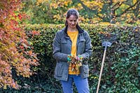 Woman holding fallen leaves and moss collected when raking lawn