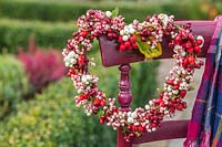 Autumnal berry wreath hanging on dark red chair