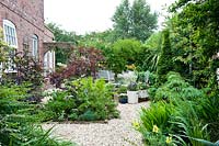 Small gravel garden and pots and decorative white furniture surrounded by trellis with climbers for privacy
