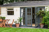 Summer house with narrow patio in front, grey painted doors and view to woodburner inside