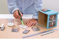 Woman using soft brush to apply PVA to the back of wrapping paper panels.