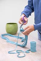 Woman using sissors to cut blue fabric cord to length