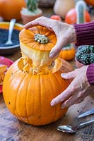 Woman removing the top off of a pumpkin