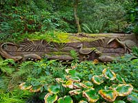 Fallen oak carved with seats and scenes of birds, fish and animals Abbotsbury Subtropical Gardens, Abbotsbury, Dorset, UK