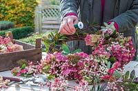 Woman using floristry wire to secure the berries, flowers and foliage