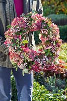 Woman holding finished wreath made with Sorbus berries, Hydrangea flowerheads and Hebe foliage