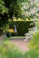 View along the gravel path at the back of the main border in the Orchard garden to the sculpture by Christopher Lisney