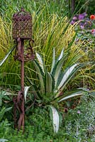An iron lamp rests beside a variegated agave.