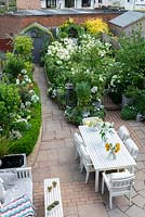 Bird's eye view of a small town garden, with dining and seating areas and white-themed borders.