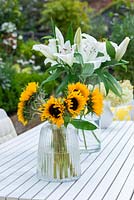 Dining table with vases of sunflowers and white lilies