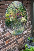 On a side wall, a domed mirror reflects distorted images of flowers in the central flower bed.