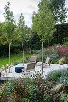 Four 'Chanticleer' ornamental pear trees are planted in the lowest seating terrace which is edged in autumn borders of of herbaceous flowering plants and ornamental grasses.