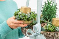 Woman placing candle holder with foliage onto hanging tray