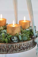 Detail of hanging advent arrangement with gold candles, Eucalyptus and Hebe foliage