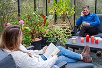 Father and daughter relaxing on lounge furniture in a greenhouse 