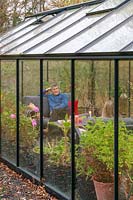 View into a greenhouse where people are sat relaxing on lounge furniture 